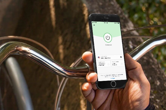 자전거를 탄 사람이 자랑스럽게 iPhone을 들고 있습니다. 해당 iPhone에서 iOS 용 ExpressVPN 앱이 실행 중입니다.