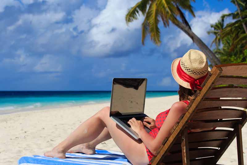 Една дама с лаптоп на плажа.